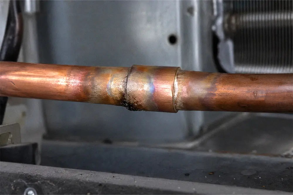 Oily residue beneath a brazed joint on a copper air conditioner refrigerant line